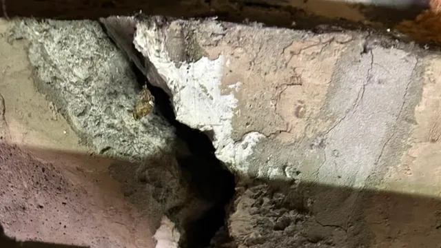 Close-up of spalled concrete broken away to a void, the kind of water and freeze-thaw damage that also pits garage floors